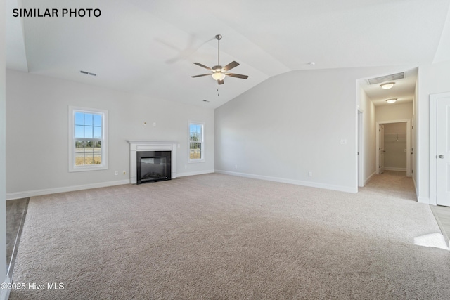 unfurnished living room with a wealth of natural light, visible vents, lofted ceiling, and light colored carpet