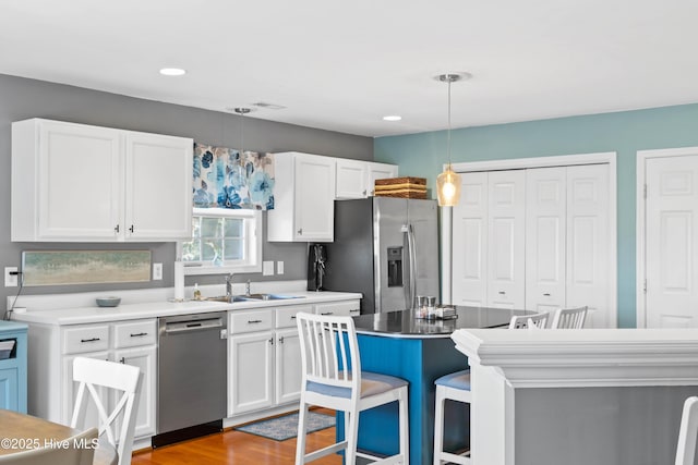 kitchen with a sink, appliances with stainless steel finishes, white cabinets, and pendant lighting