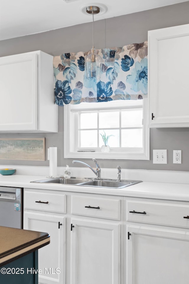 kitchen featuring white cabinets, dishwasher, light countertops, and a sink