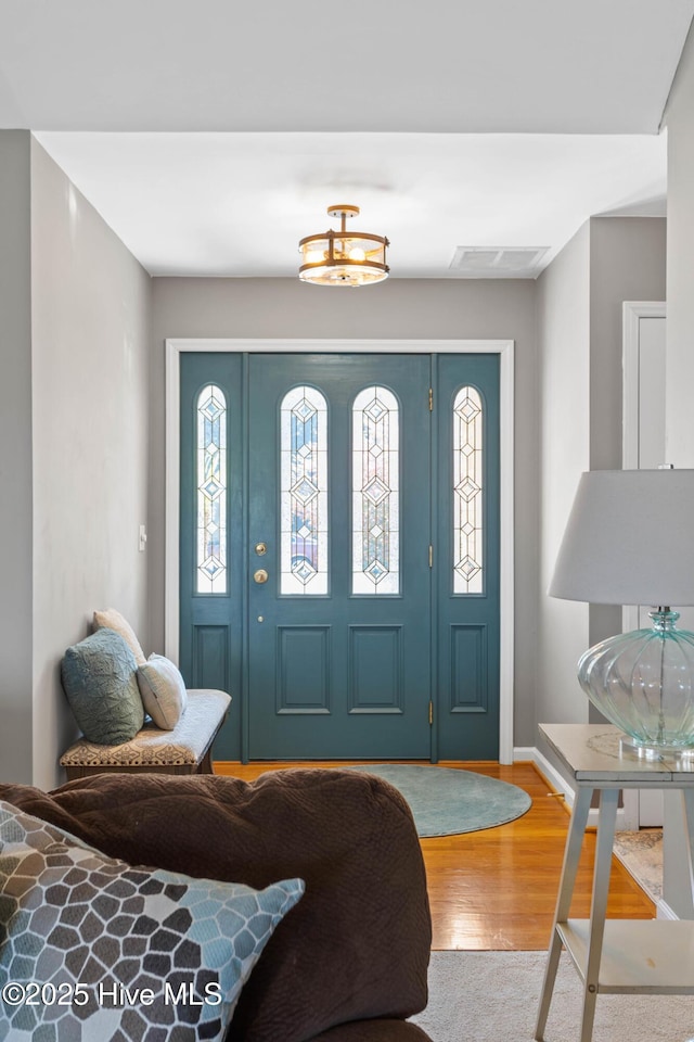 foyer featuring wood finished floors, visible vents, and baseboards