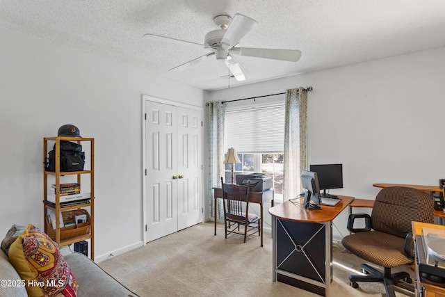 office space with baseboards, light carpet, a textured ceiling, and ceiling fan