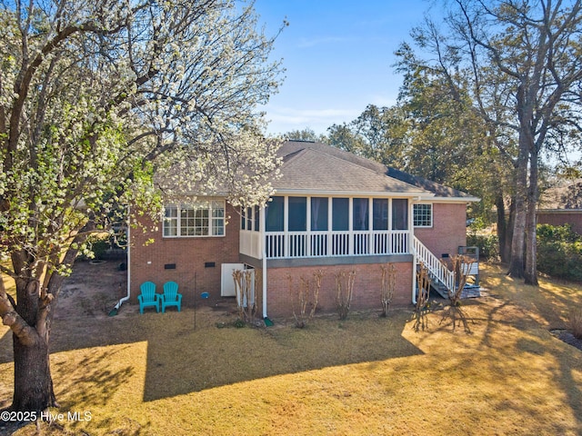 back of house featuring a lawn, roof with shingles, a sunroom, brick siding, and stairs