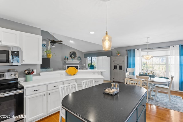 kitchen with white cabinetry, light wood-style flooring, ceiling fan with notable chandelier, and appliances with stainless steel finishes