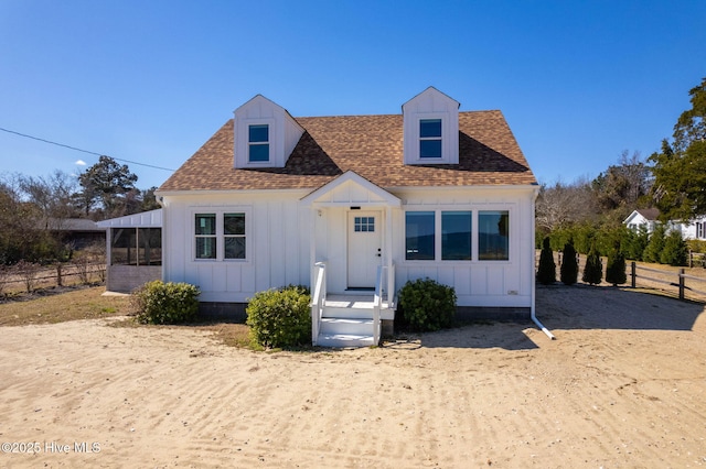 view of front facade with fence, board and batten siding, and a shingled roof