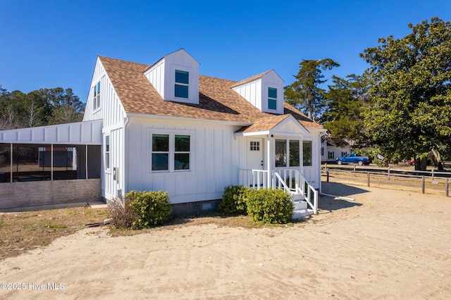 view of front of home featuring fence, board and batten siding, and roof with shingles