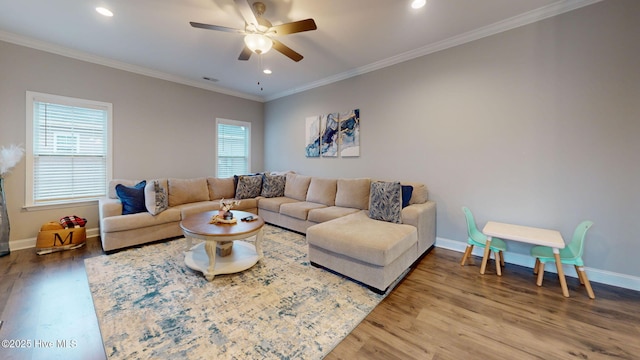 living room featuring wood finished floors, a ceiling fan, visible vents, baseboards, and ornamental molding