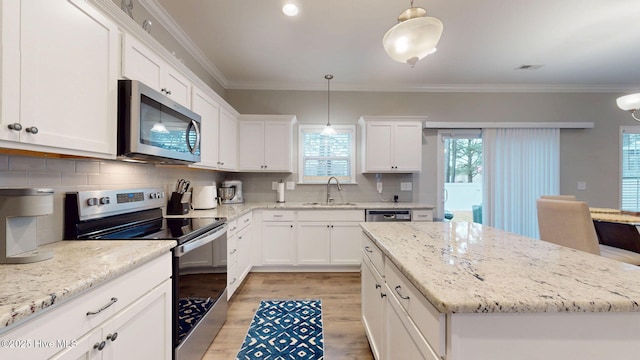 kitchen featuring a center island, appliances with stainless steel finishes, a sink, and ornamental molding