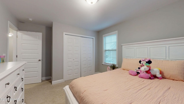 bedroom featuring baseboards, a closet, and light colored carpet