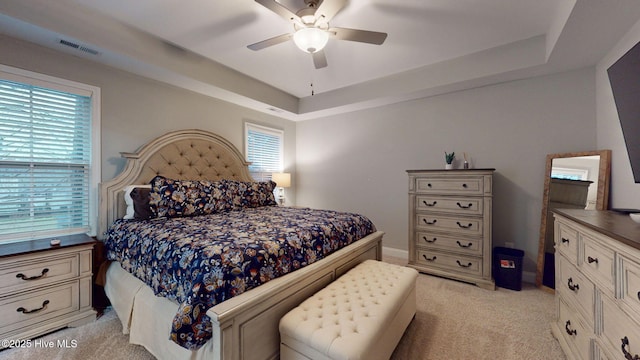 bedroom featuring light carpet, a raised ceiling, visible vents, and baseboards