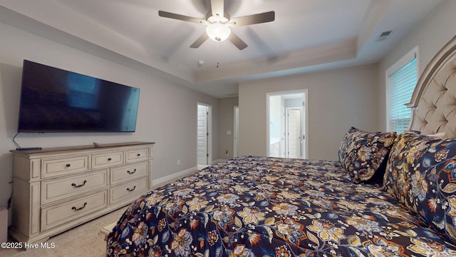 carpeted bedroom with a tray ceiling, visible vents, ceiling fan, and baseboards