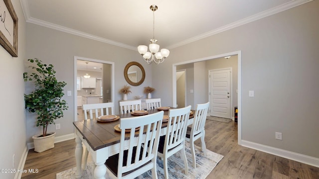 dining area with light wood finished floors, a notable chandelier, baseboards, and crown molding