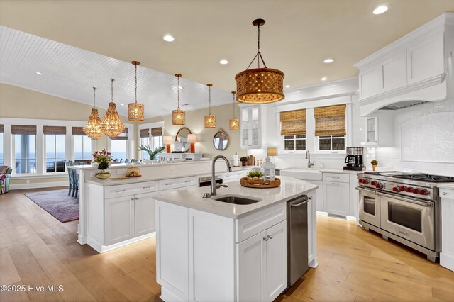 kitchen featuring light countertops, appliances with stainless steel finishes, light wood-style floors, a sink, and an island with sink