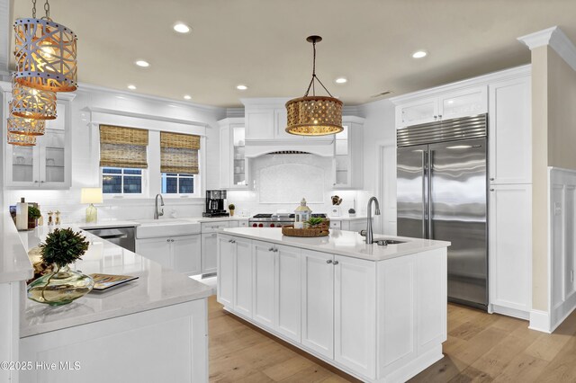 kitchen with appliances with stainless steel finishes, light wood-style floors, a sink, and an island with sink