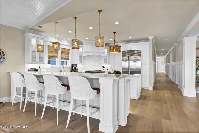 kitchen featuring a peninsula, stainless steel built in fridge, a kitchen breakfast bar, and crown molding