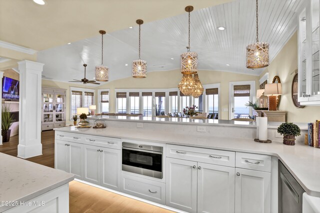 kitchen featuring wood finished floors, vaulted ceiling, light countertops, ornate columns, and pendant lighting