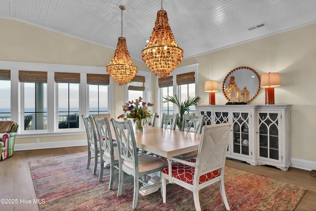 dining area with lofted ceiling, wood finished floors, visible vents, and a notable chandelier