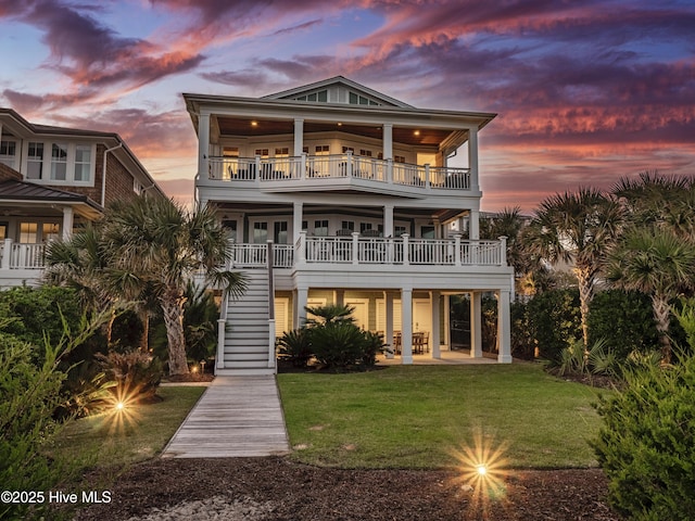 back of property with stairs, a yard, a patio, and a balcony