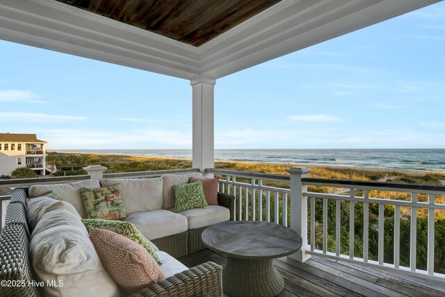 balcony with an outdoor hangout area, a water view, and a view of the beach