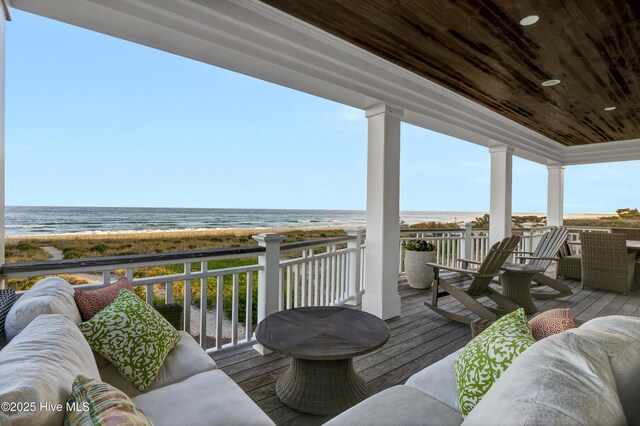 wooden deck with a water view and a beach view