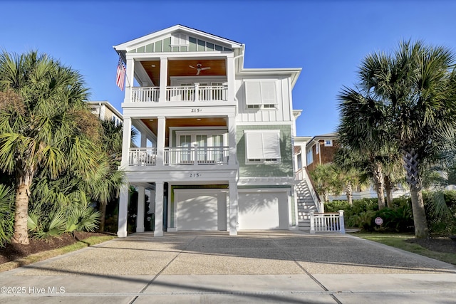 coastal inspired home with stairs, concrete driveway, board and batten siding, and a balcony