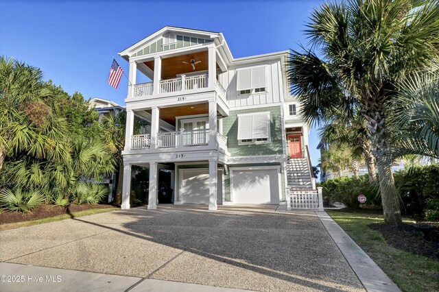 coastal inspired home featuring driveway, board and batten siding, a ceiling fan, a balcony, and a carport