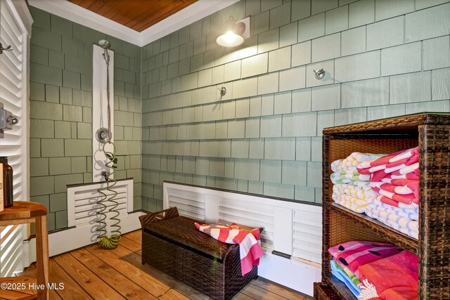 interior space with wood finished floors, tile walls, and crown molding