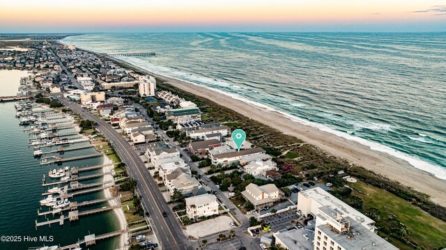 aerial view at dusk with a water view and a beach view