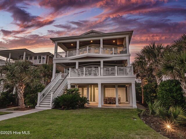 view of front facade with stairs, a patio, a front lawn, and a balcony