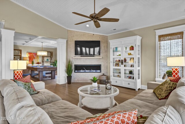 living room featuring a large fireplace, coffered ceiling, decorative columns, and wood finished floors