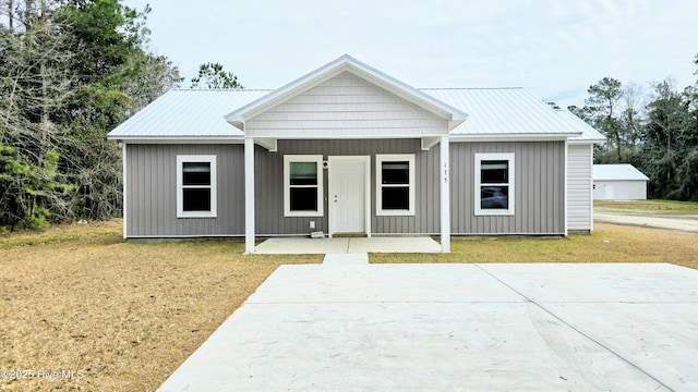 view of front of house featuring board and batten siding, metal roof, and a front lawn