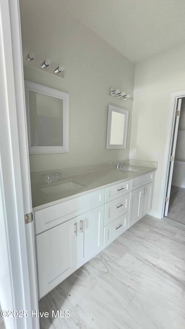 bathroom with marble finish floor, double vanity, and a sink