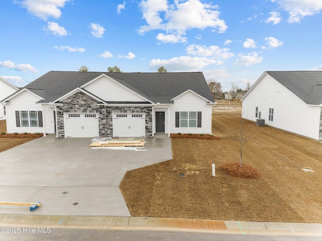 view of front facade featuring a shingled roof, a garage, cooling unit, stone siding, and driveway