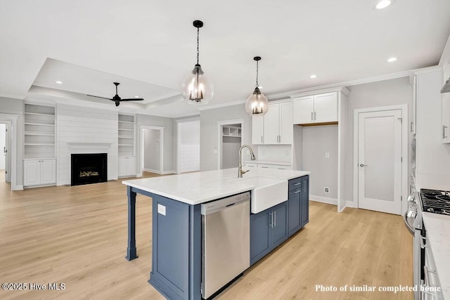 kitchen with stainless steel appliances, a raised ceiling, light countertops, white cabinets, and blue cabinets