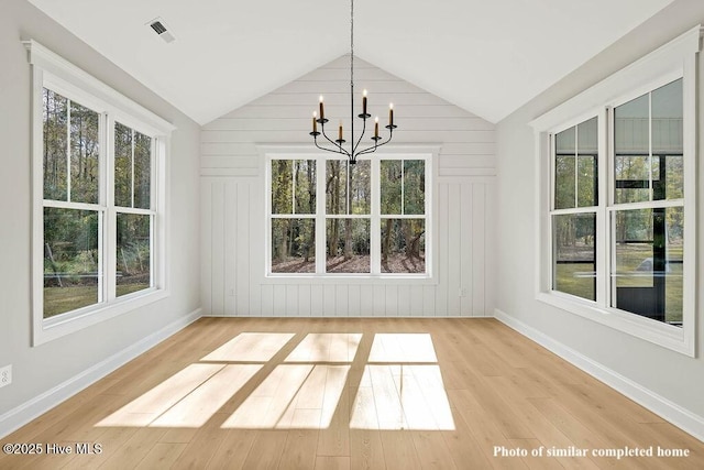 unfurnished dining area featuring visible vents, baseboards, lofted ceiling, light wood-style flooring, and a chandelier