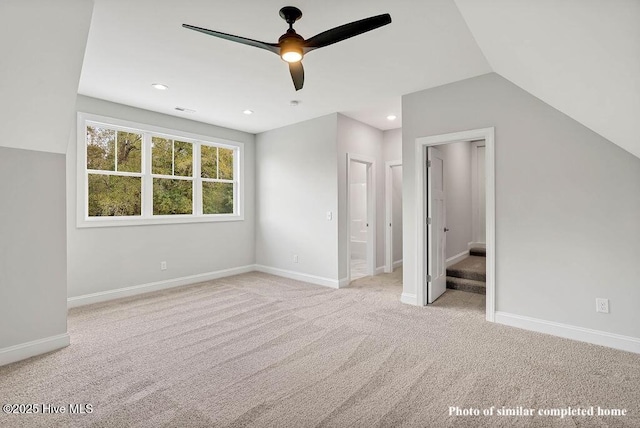 unfurnished bedroom featuring light carpet, lofted ceiling, and baseboards