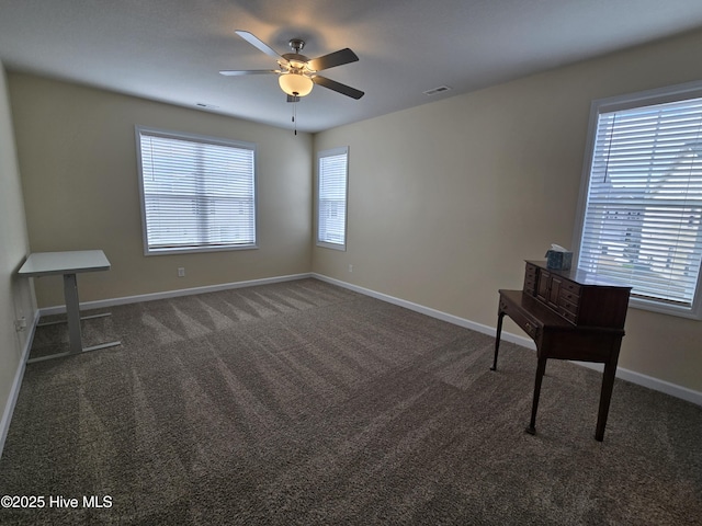 interior space with a healthy amount of sunlight, visible vents, dark carpet, and baseboards