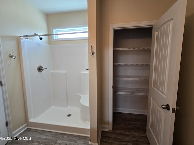 full bathroom featuring a shower, wood finished floors, and baseboards