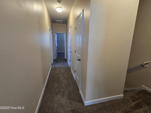 hall featuring carpet floors, baseboards, and an upstairs landing