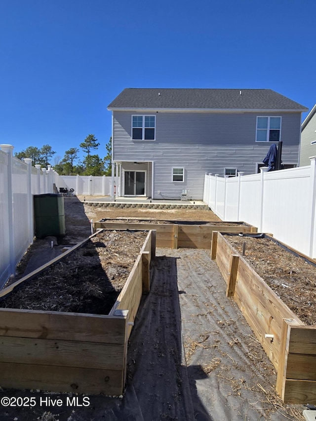 rear view of house featuring a fenced backyard and a vegetable garden