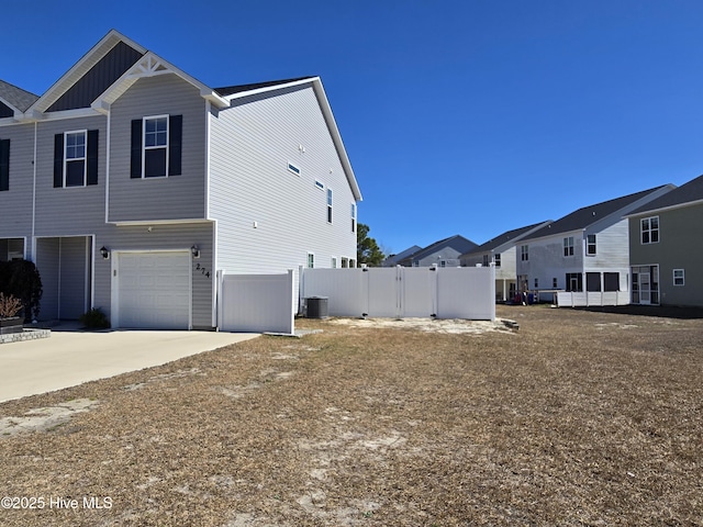 view of property exterior with a garage, driveway, fence, cooling unit, and board and batten siding