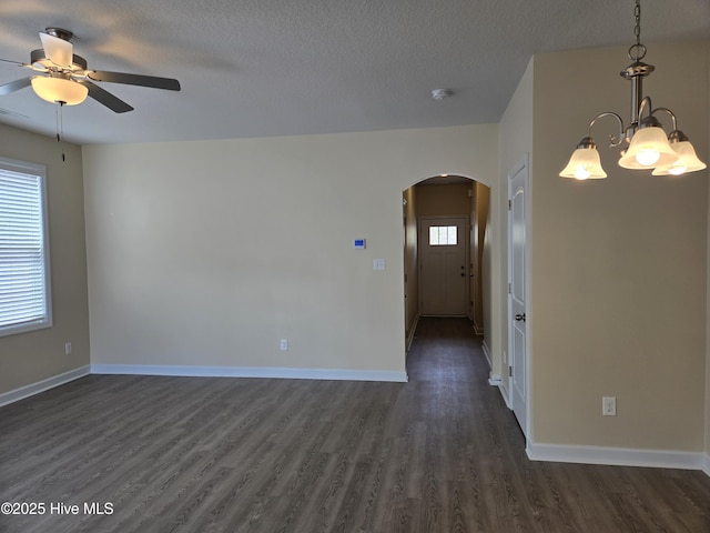 unfurnished room featuring arched walkways, ceiling fan, a textured ceiling, baseboards, and dark wood finished floors