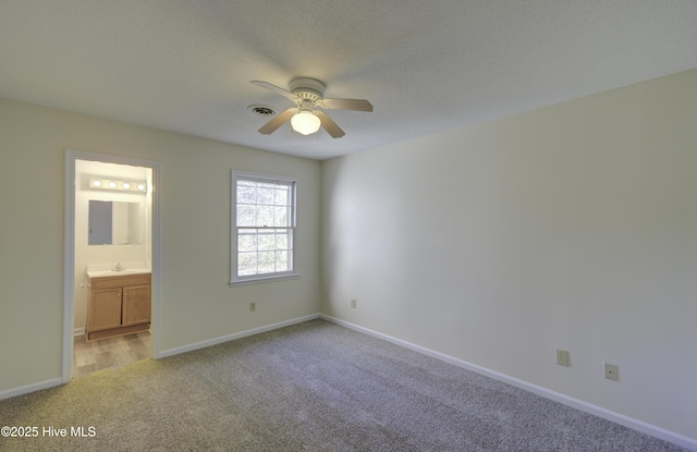 unfurnished bedroom with visible vents, light carpet, connected bathroom, a sink, and baseboards