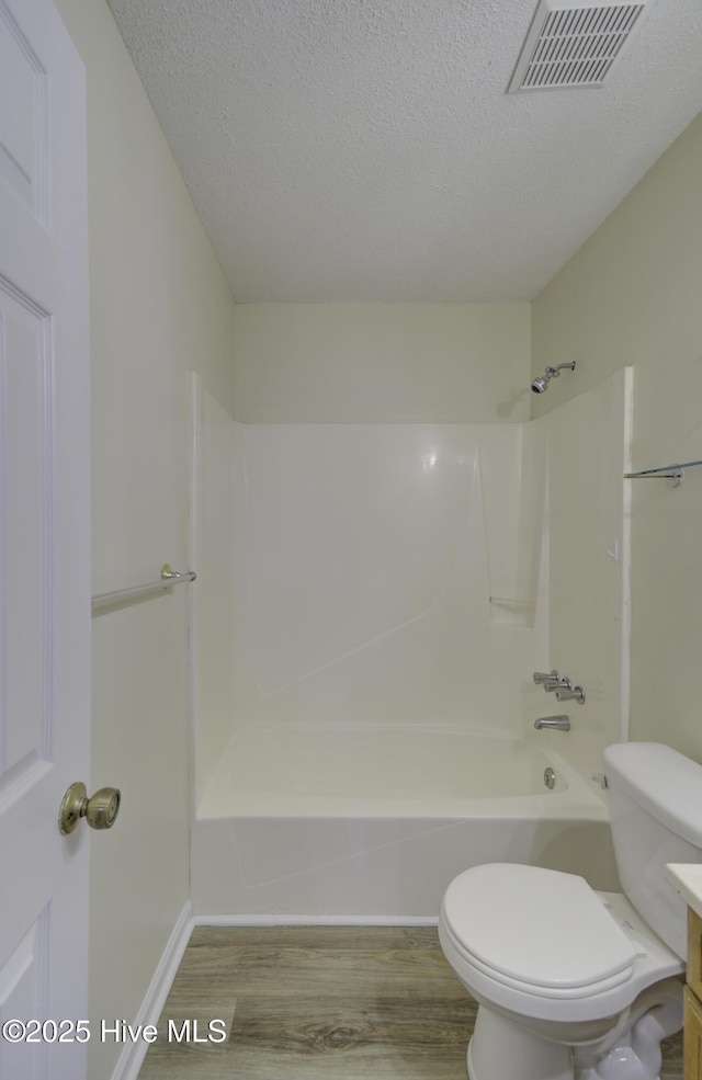 full bath with a textured ceiling, toilet, wood finished floors, visible vents, and bathing tub / shower combination