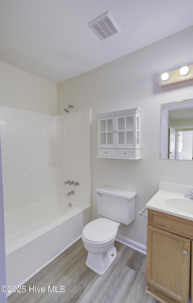 full bathroom with a textured ceiling, toilet, wood finished floors, vanity, and visible vents