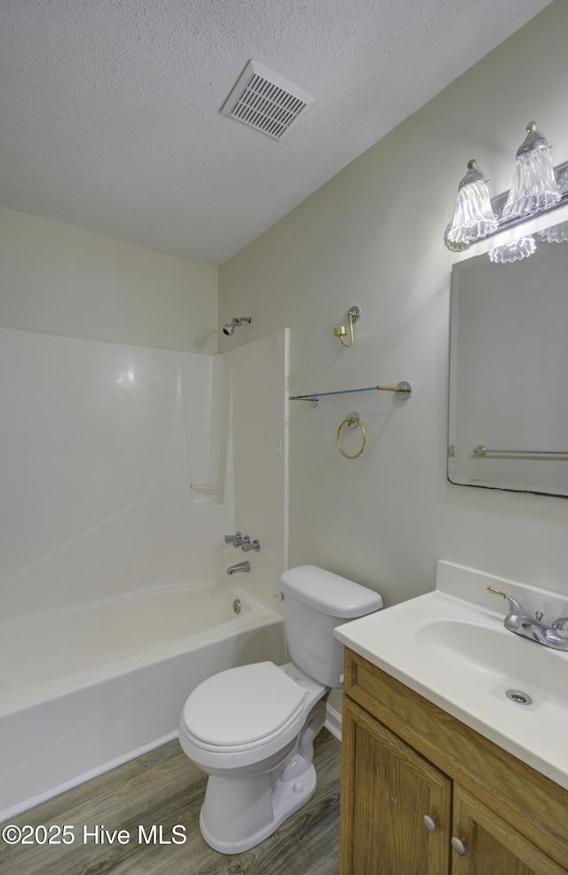 full bath featuring visible vents, toilet, wood finished floors, a textured ceiling, and vanity