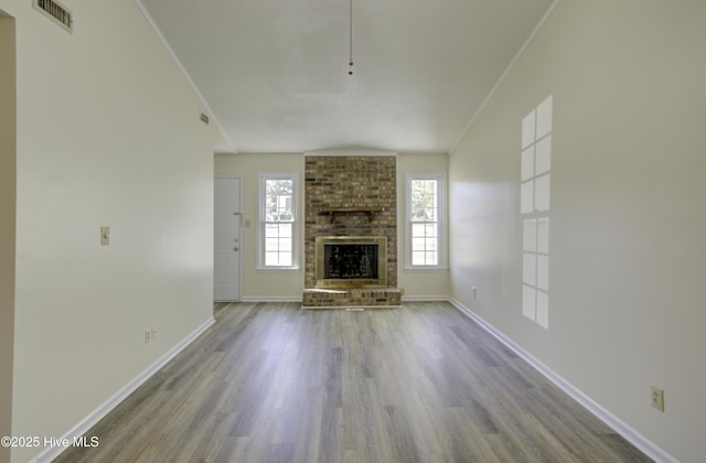 unfurnished living room featuring baseboards, visible vents, ornamental molding, wood finished floors, and a brick fireplace