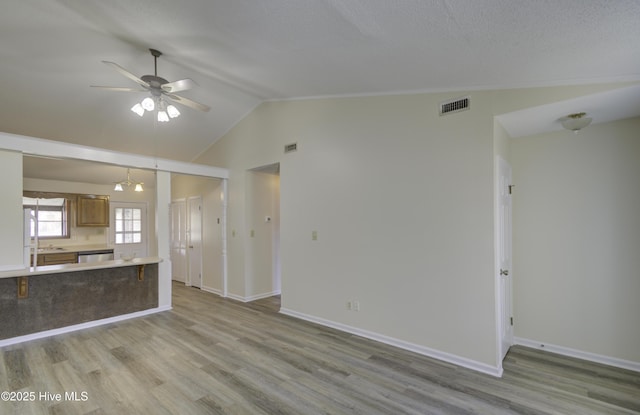 unfurnished living room featuring lofted ceiling, visible vents, light wood-style flooring, and baseboards