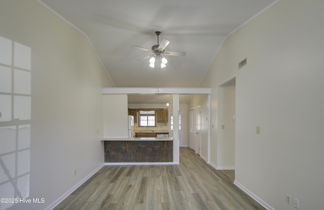 kitchen with visible vents, freestanding refrigerator, vaulted ceiling, wood finished floors, and a peninsula