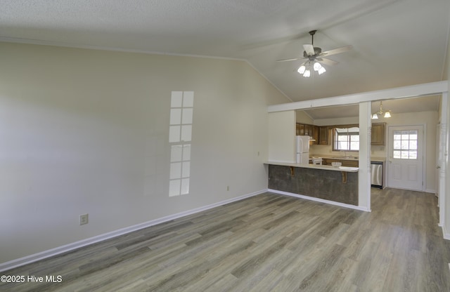 unfurnished living room with lofted ceiling, light wood-style floors, baseboards, and a ceiling fan