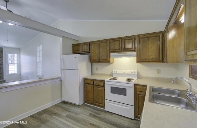 kitchen featuring lofted ceiling, light countertops, a sink, white appliances, and under cabinet range hood